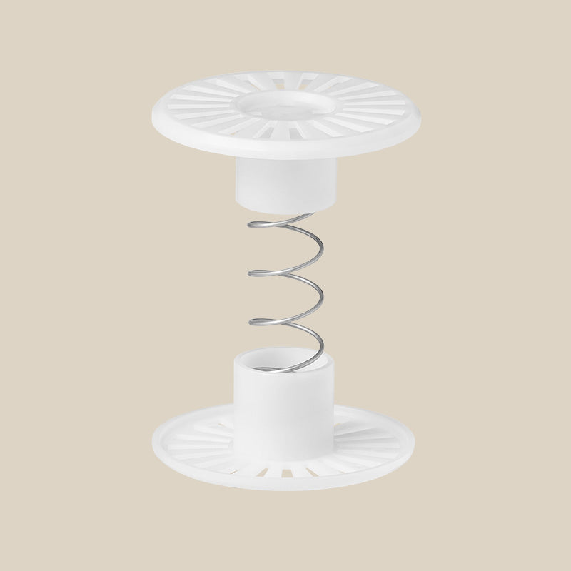 A white breathing monitor sensor adapter with a circular base and a spring mechanism, designed for use with breathing monitors.