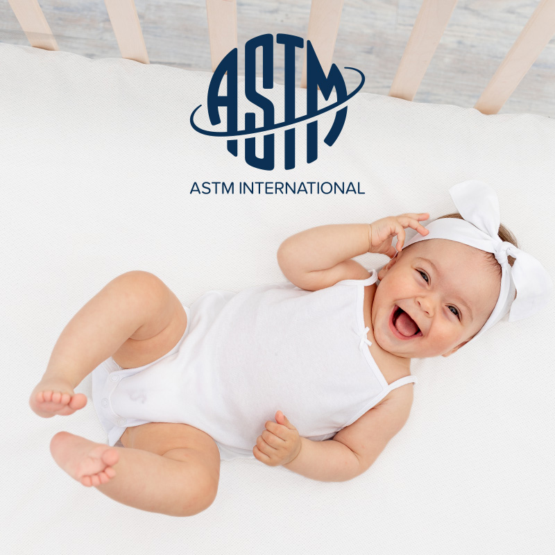 happy supine baby on numu air breathable infant mattress with logo of ASTM