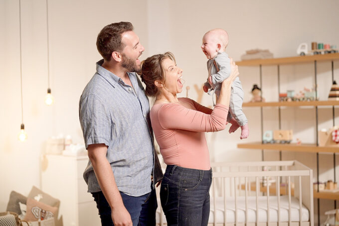 happy father and happy mother holding happy baby in front of her