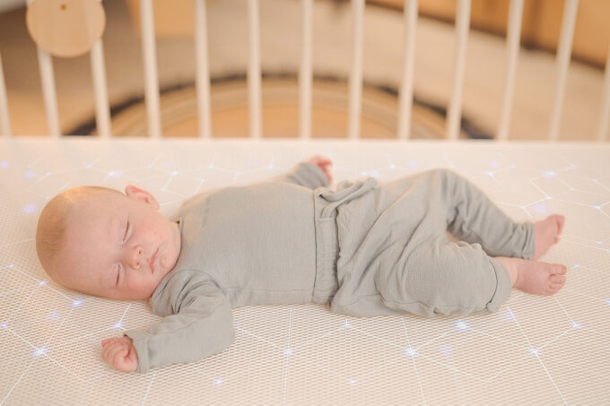 baby sleeping in supine position on numu air comfortable crib mattress with glowing filaments in it