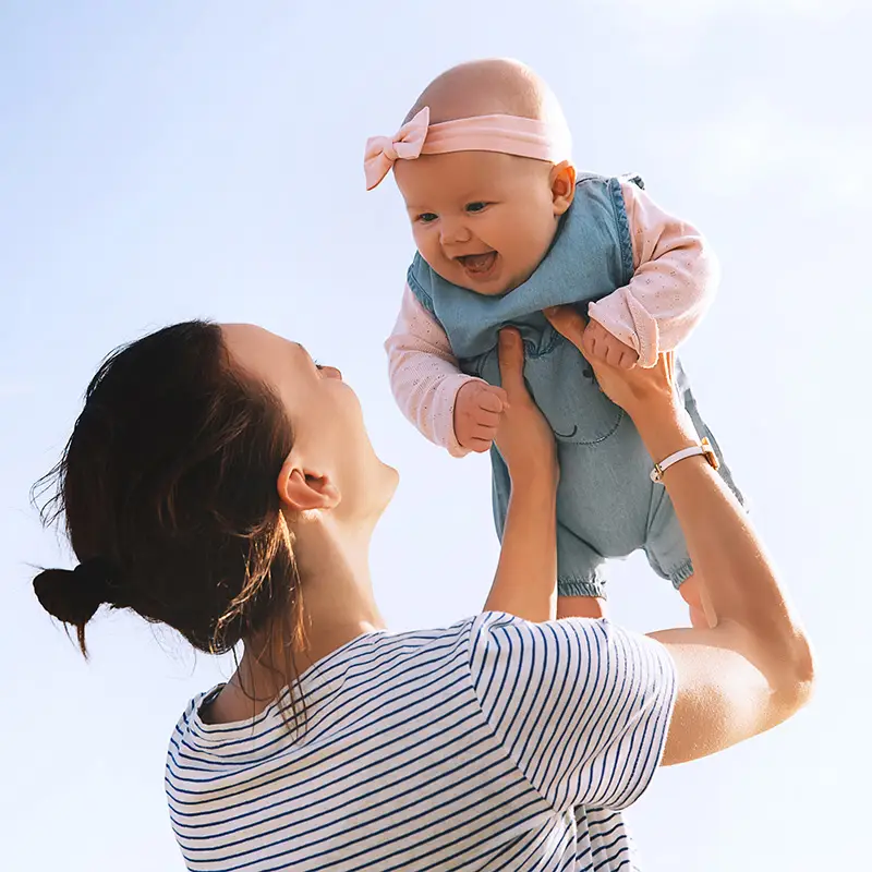 mother holding baby above her face