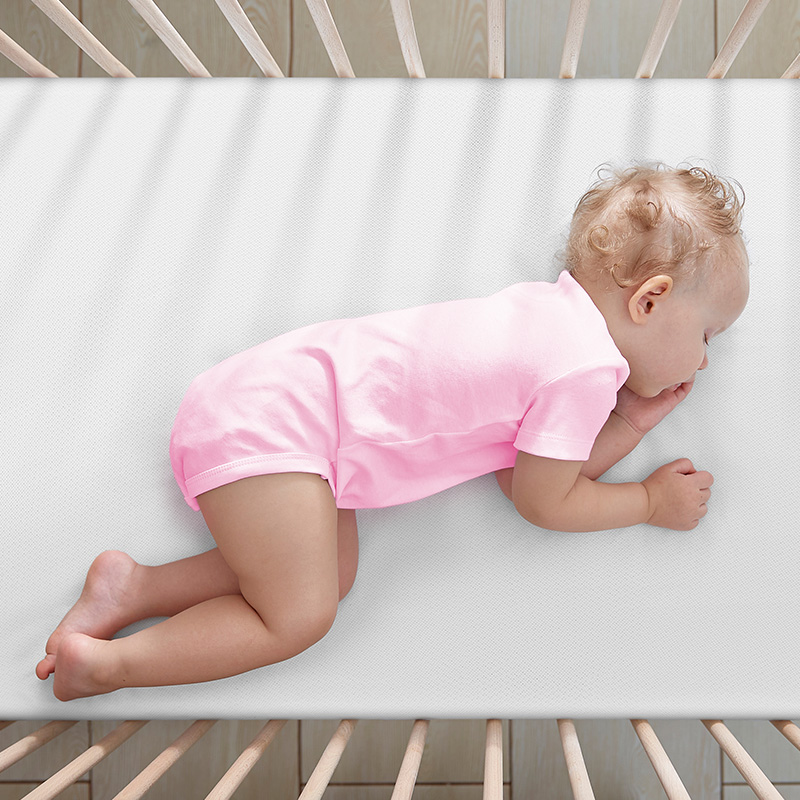 baby lying on side on numu air non toxic crib mattress viewed from above