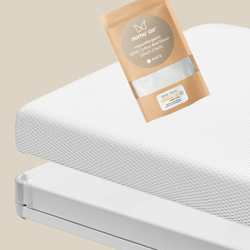 breathe-through bedsheet in its package next to numu air mattress for infant crib