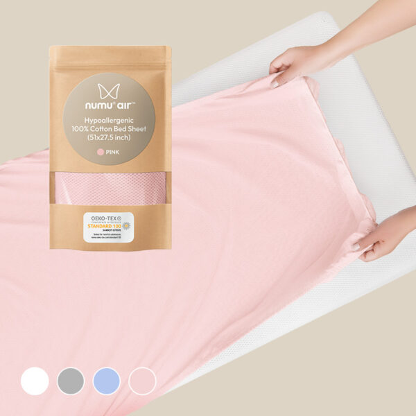 hands putting pink perforated breathe-through bedsheet on numu air infant crib mattress