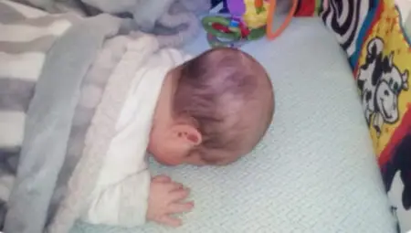 another prone baby lying in crib on numu air best rated infant mattress seen from above